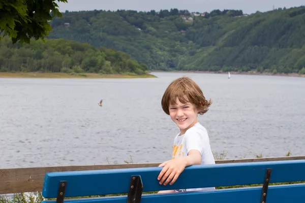 Kind sitzt auf einer Bank — Stockfoto