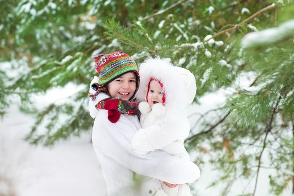 Boy hugging his baby sister in winter park