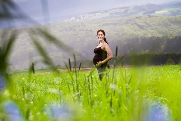 Pregnant woman walking in a field — Stock Photo, Image