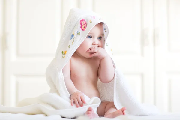 Baby girl sitting under a hooded towel after bath