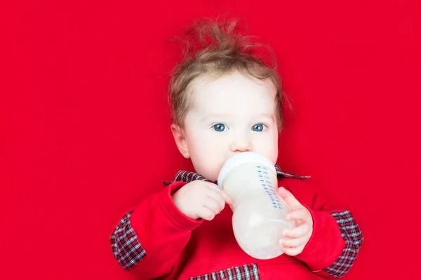 Baby drinking milk on a red blanket — Stock Photo, Image