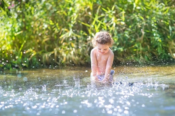 Baby girl splashing in a river — Stock Photo, Image