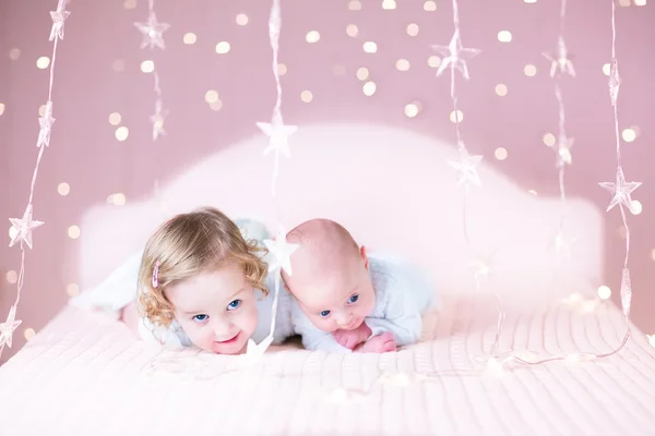 Neugeborenes Baby und kleine Schwester spielen auf einem weißen Bett — Stockfoto