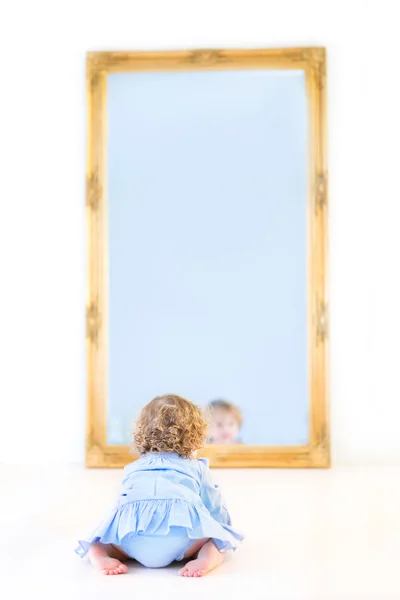 Menina de pé na frente de um grande espelho — Fotografia de Stock