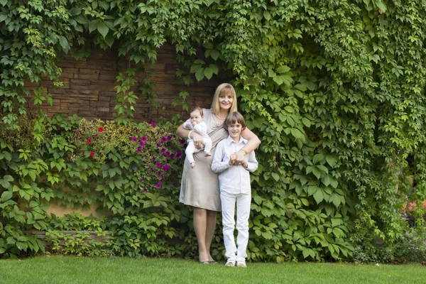 Woman with two kids in formal clothes in the garden — Stock Photo, Image