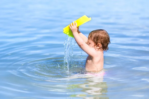 Bebê brincando na água em uma praia — Fotografia de Stock