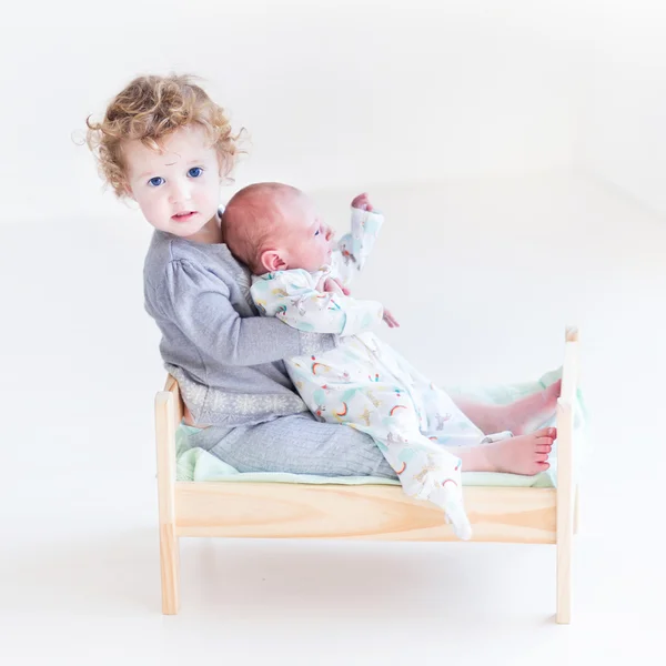 Peuter meisje spelen met haar pasgeboren broertje — Stockfoto