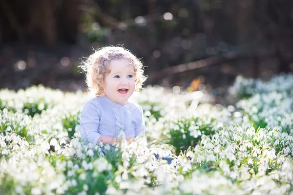 Menina brincando com as primeiras flores da primavera — Fotografia de Stock