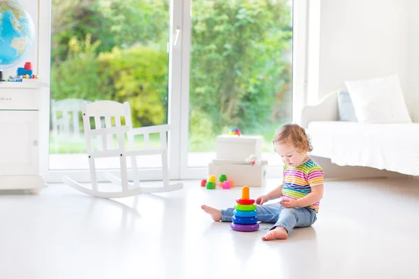 Toddler girl playing with a colorful pyramid — Stock Photo, Image
