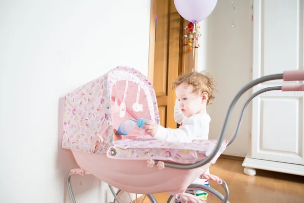 Baby girl with a doll stroller — Stock Photo, Image