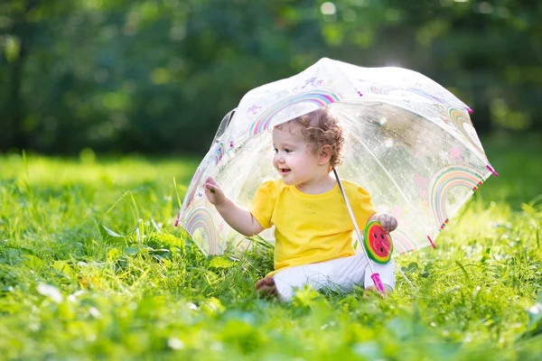 Girl playing in the garden under an umbrella — Stock Photo, Image