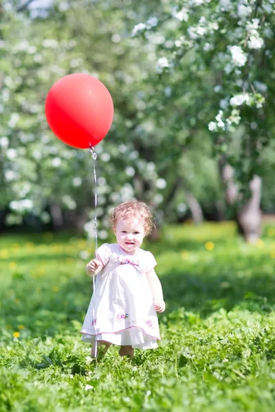 Красивая маленькая девочка играет с цветами — стоковое фото