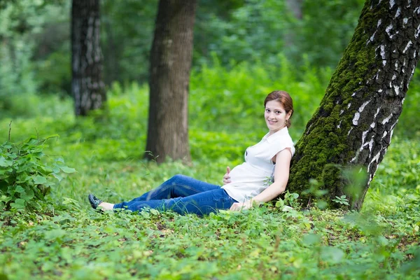 Těhotná žena relaxační v parku — Stock fotografie