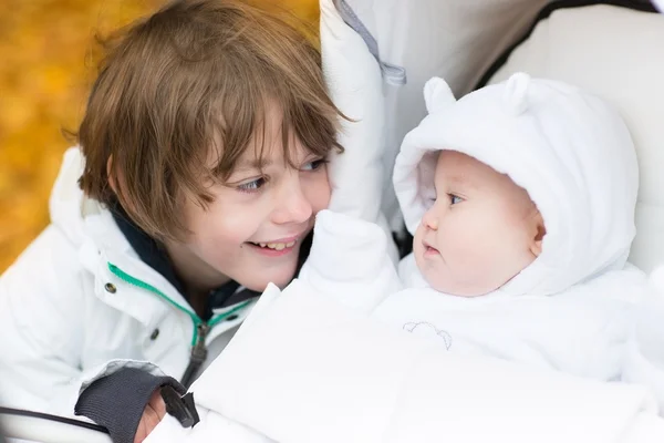 Bror leker med hans lillasyster som sitter i en barnvagn — Stockfoto