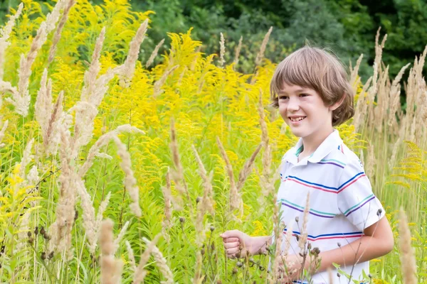 Niño jugando en un campo de flores amarillas — Foto de Stock