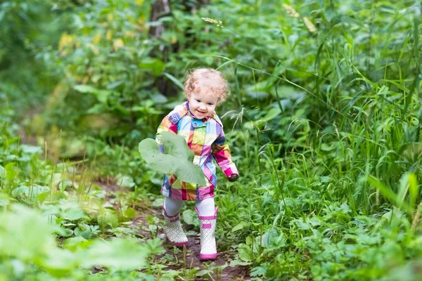 Niña jugando con hojas grandes en un parque —  Fotos de Stock