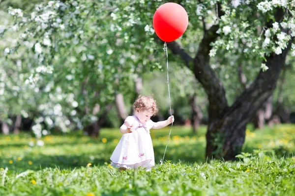 Baby girl playing with a red balloon — Stock Photo, Image