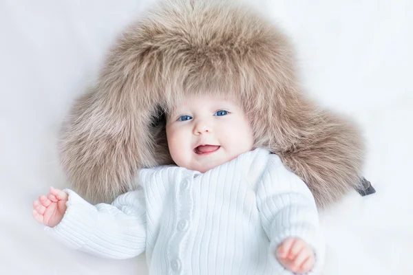 Baby girl with big blue eyes wearing a huge winter hat — Stock Photo, Image