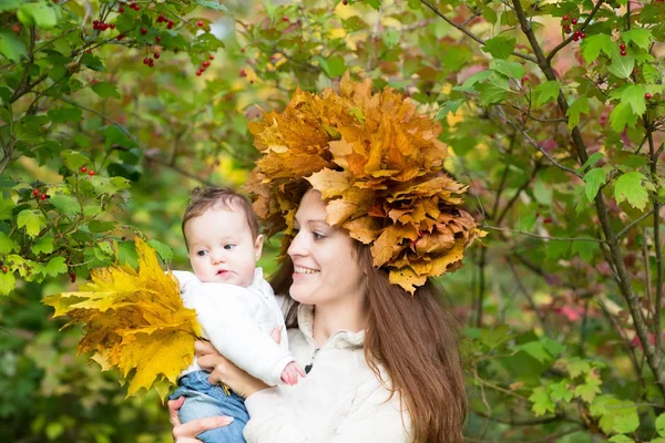 Mutter hält ein kleines Mädchen mit einem Ahornblatt-Kranz in der Hand — Stockfoto