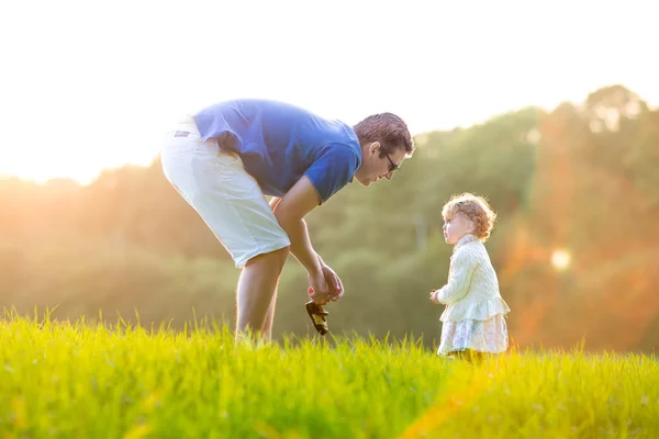 Отец играет со своей маленькой дочерью в поле — стоковое фото