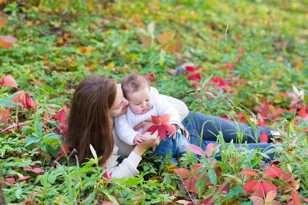 Mother and her baby daughter lying among red leaves — Stock Photo, Image