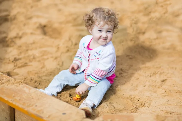 Baby girl digging in sand — Stock Photo, Image