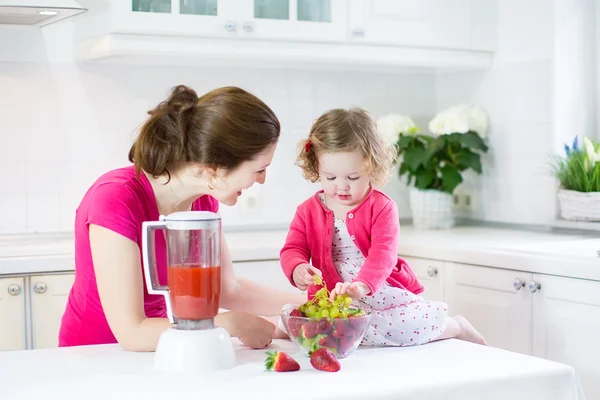 Irl y su joven madre haciendo jugo de fresa fresco —  Fotos de Stock