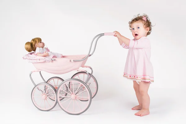 Meisje van de baby wandelen met een pop wandelwagen — Stockfoto