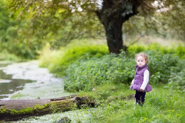 Baby girl playing at a river shore — Stock Photo, Image