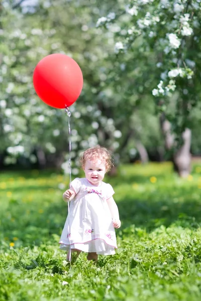 Baby girl playing with a red balloon — Stock Photo, Image