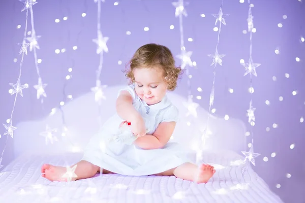 Kleinkind Mädchen spielt auf einem weißen Bett — Stockfoto
