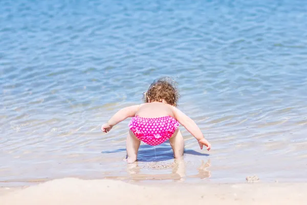 Bebê brincando na água em uma praia — Fotografia de Stock