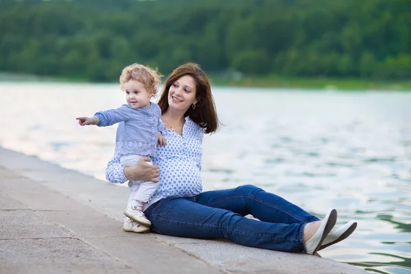 Schwangere Mutter und ihre entzückende lockige kleine Tochter — Stockfoto