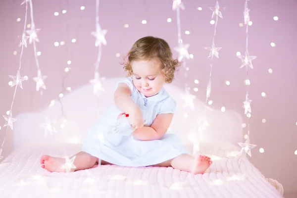 Menina da criança jogando em uma cama branca — Fotografia de Stock