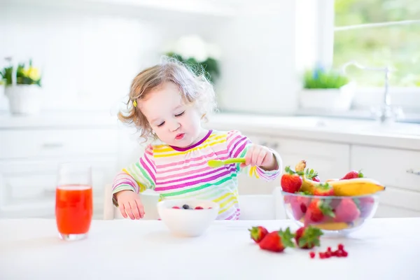 Kleinkind beim Frühstück trinkt Saft und isst Cornflakes mit Erdbeere — Stockfoto