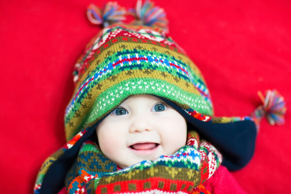 Ребенок в разноцветной вязаной шляпе и шарфе
