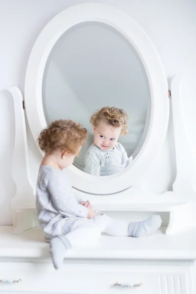 Meisje van de baby haar reflectie in een spiegel kijken — Stockfoto