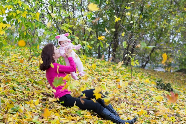 Mother holding her baby daughter under a tree — Stock Photo, Image