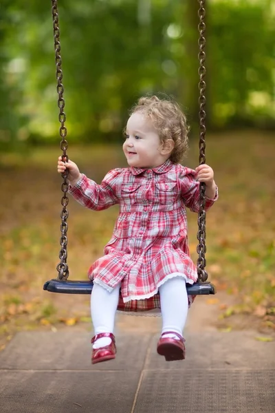 Bebê menina montando em um balanço — Fotografia de Stock