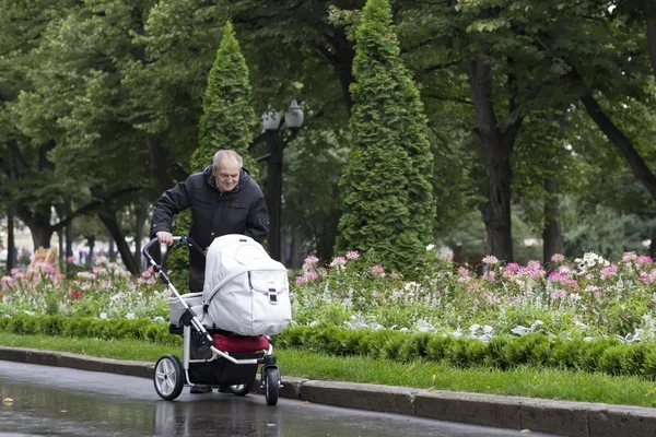 Groot-grootvader wandelen met een kinderwagen op een koude regenachtige dag — Stockfoto