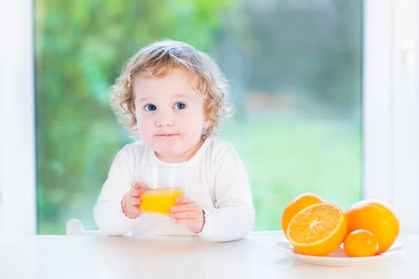 Cute little toddler girl drinking orange juice sitting — Stock Photo, Image