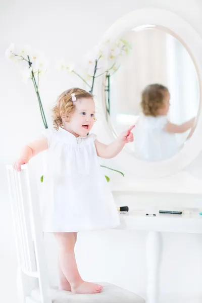 Tddler girl playing at a white mirror — Stock Photo, Image