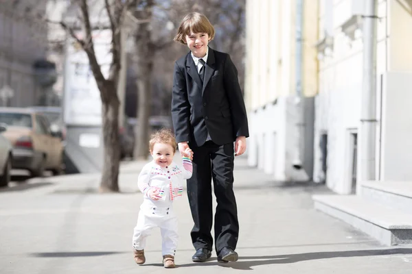 Brother and sister walking on a sunny street — Stock Photo, Image