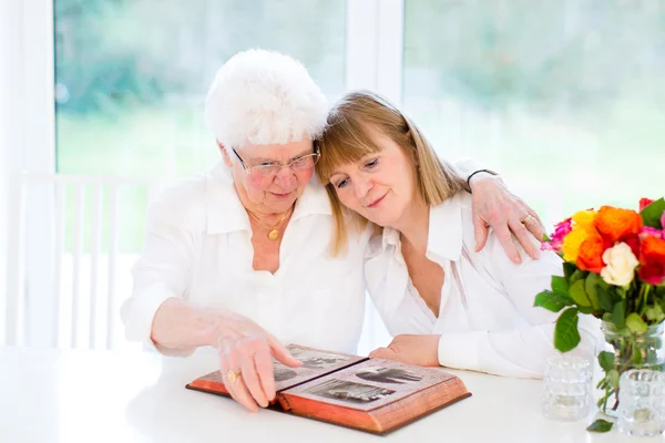 Woman and her mother watching photo album — Stock Photo, Image