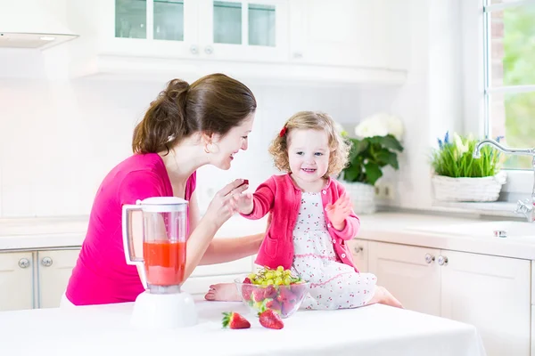 Irl and her young mother making fresh strawberry juice — Stock Photo, Image