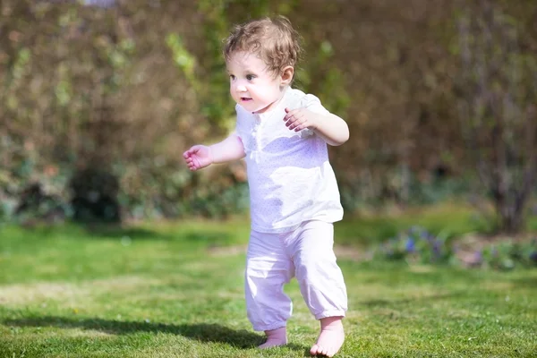 Förtjusande baby flicka som leker i en trädgård — Stockfoto