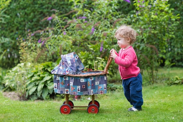 Niña jugando con un cochecito de muñeca — Foto de Stock