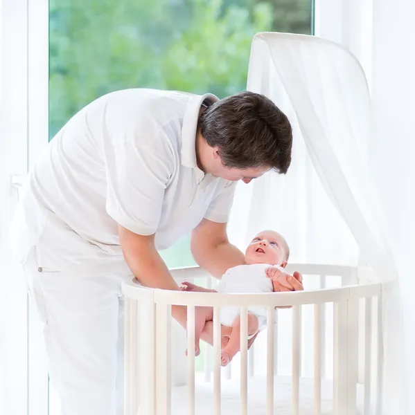 Young smiling father putting his newborn baby — Stock Photo, Image