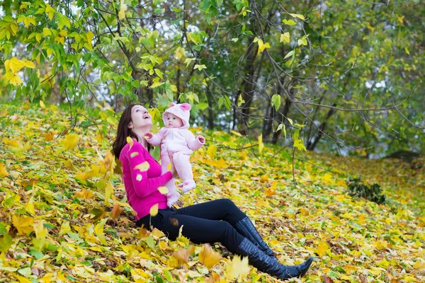 Mother holding her baby daughter under a tree — Stock Photo, Image