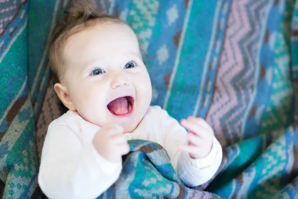 Laughing happy baby under a warm blanket